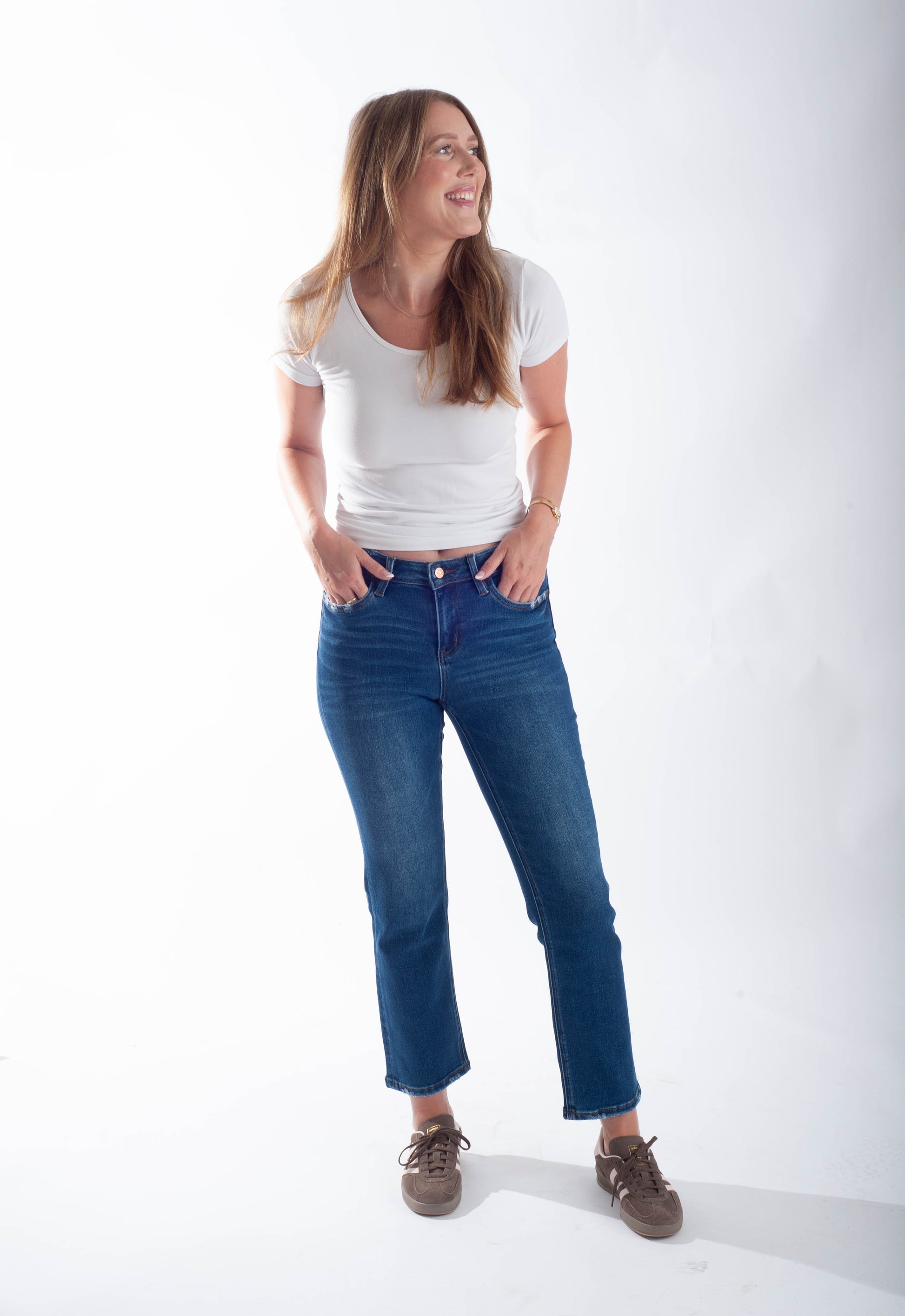 Woman wearing a white t-shirt and blue jeans standing against a white background
