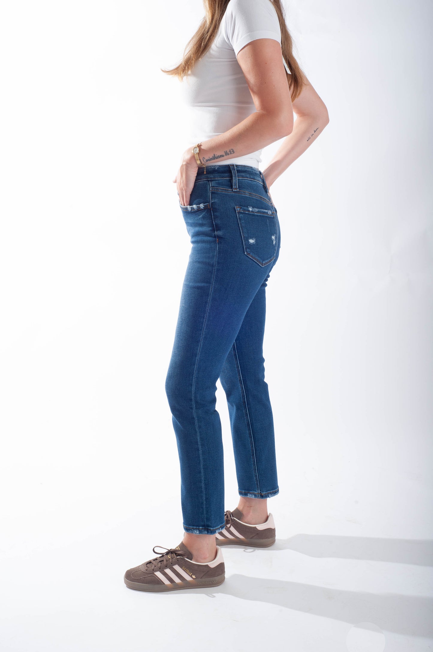 Person wearing blue jeans and a white top on a white background