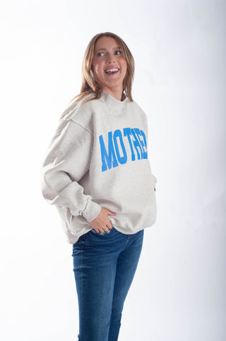Woman wearing a gray sweatshirt with 'MOTHER' printed in blue on a white background
