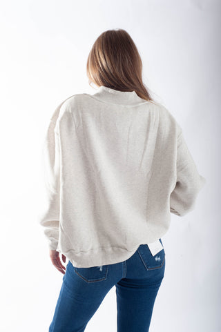 Person wearing a light gray jacket and blue jeans on a white background
