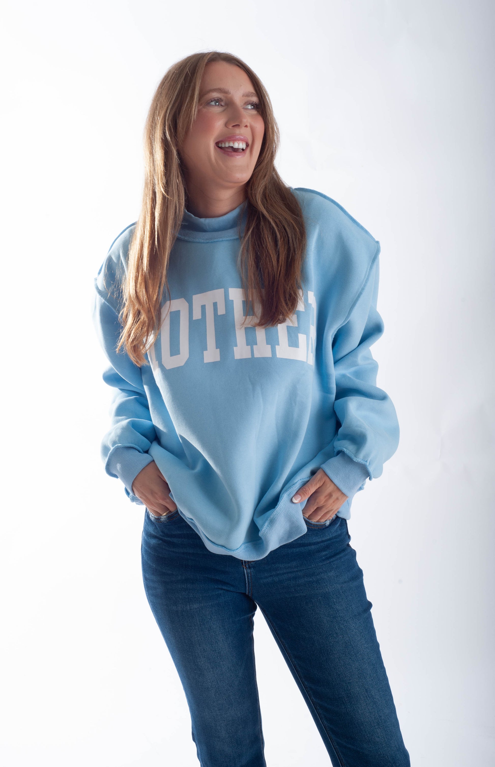 Woman wearing a light blue sweatshirt with 'Mother' text on a white background