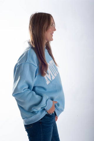 Woman wearing a light blue sweatshirt with text on a white background