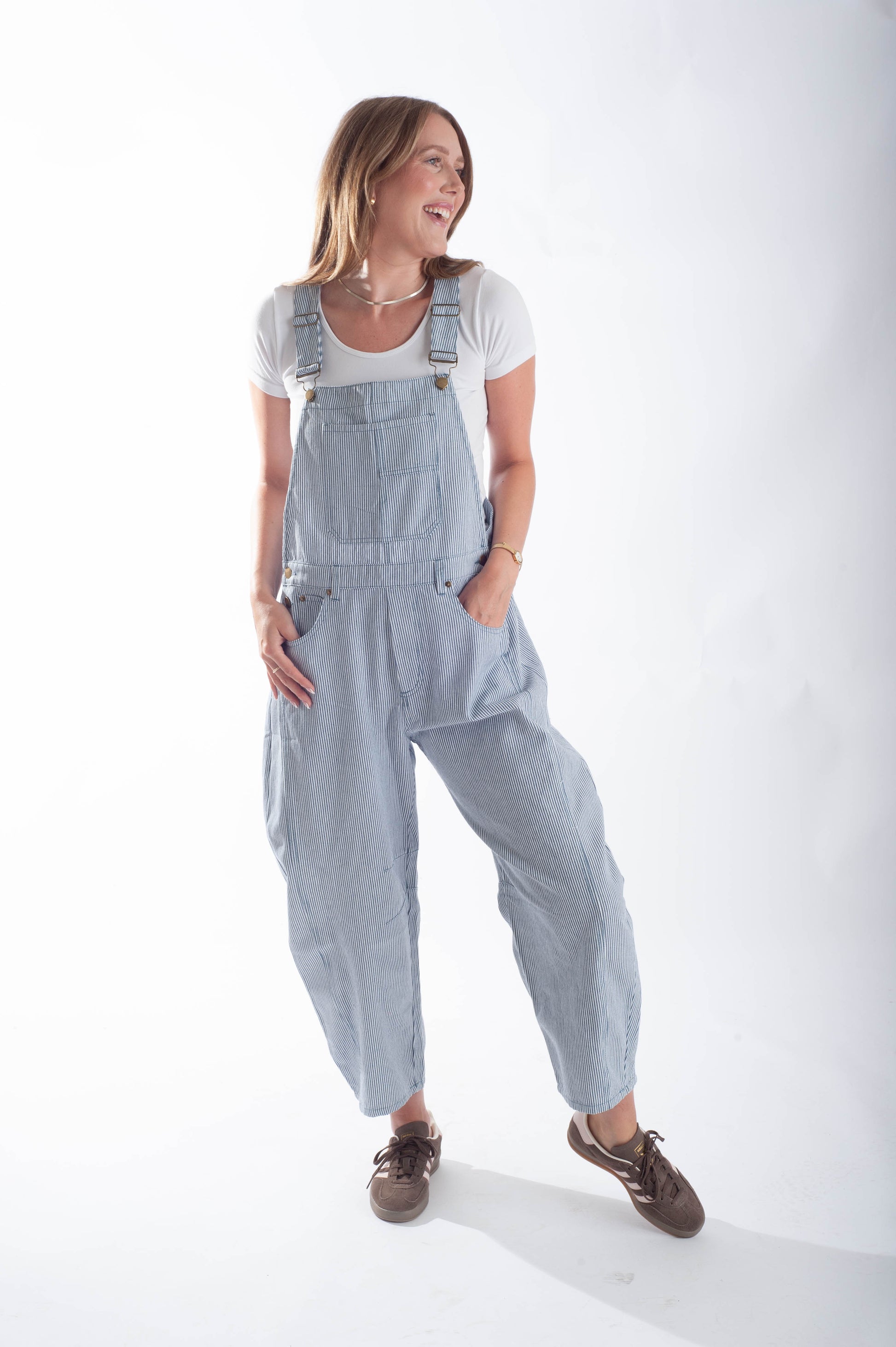 Woman wearing light blue striped overalls on a white background