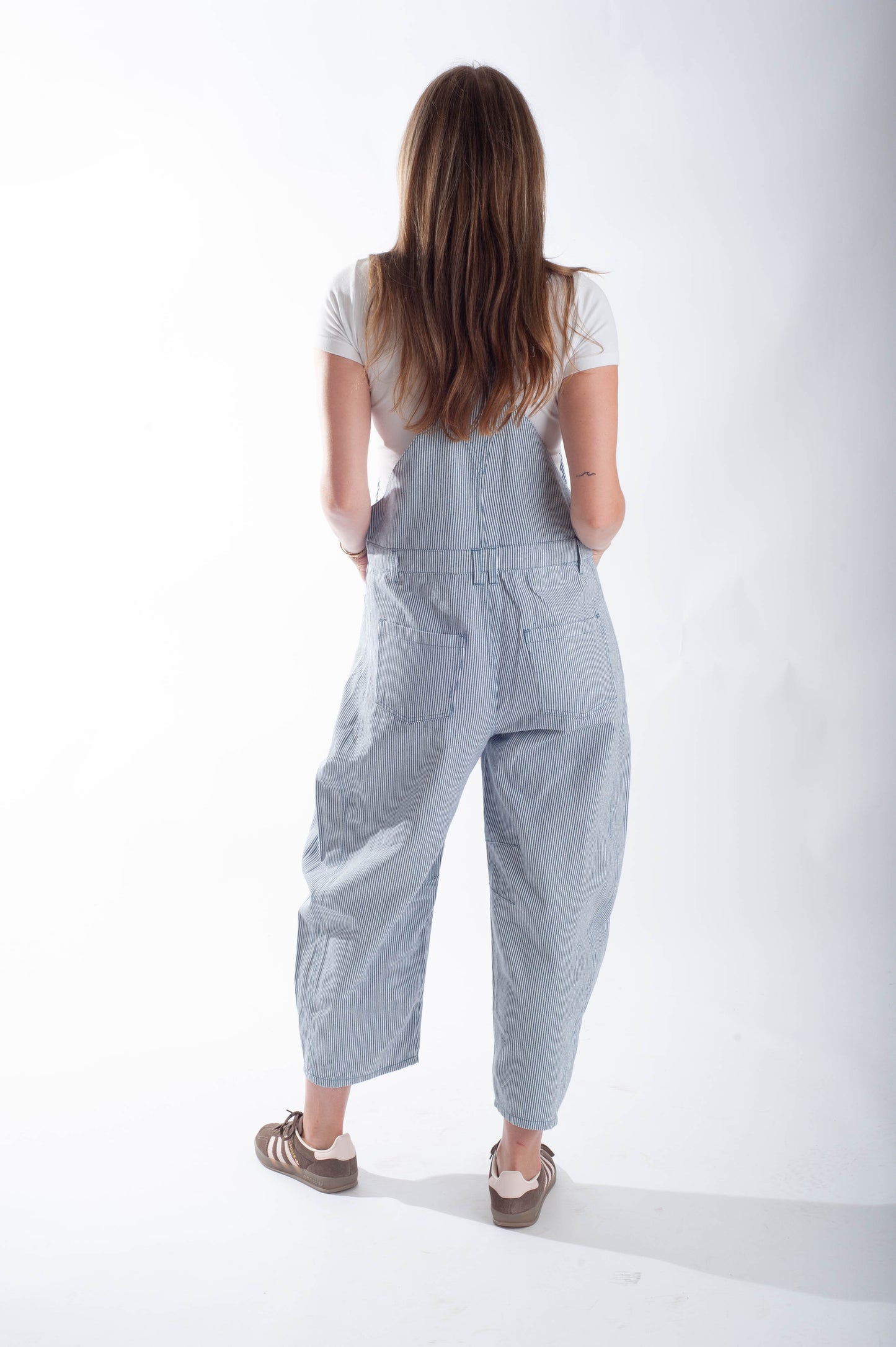 Person wearing light blue overalls on a white background