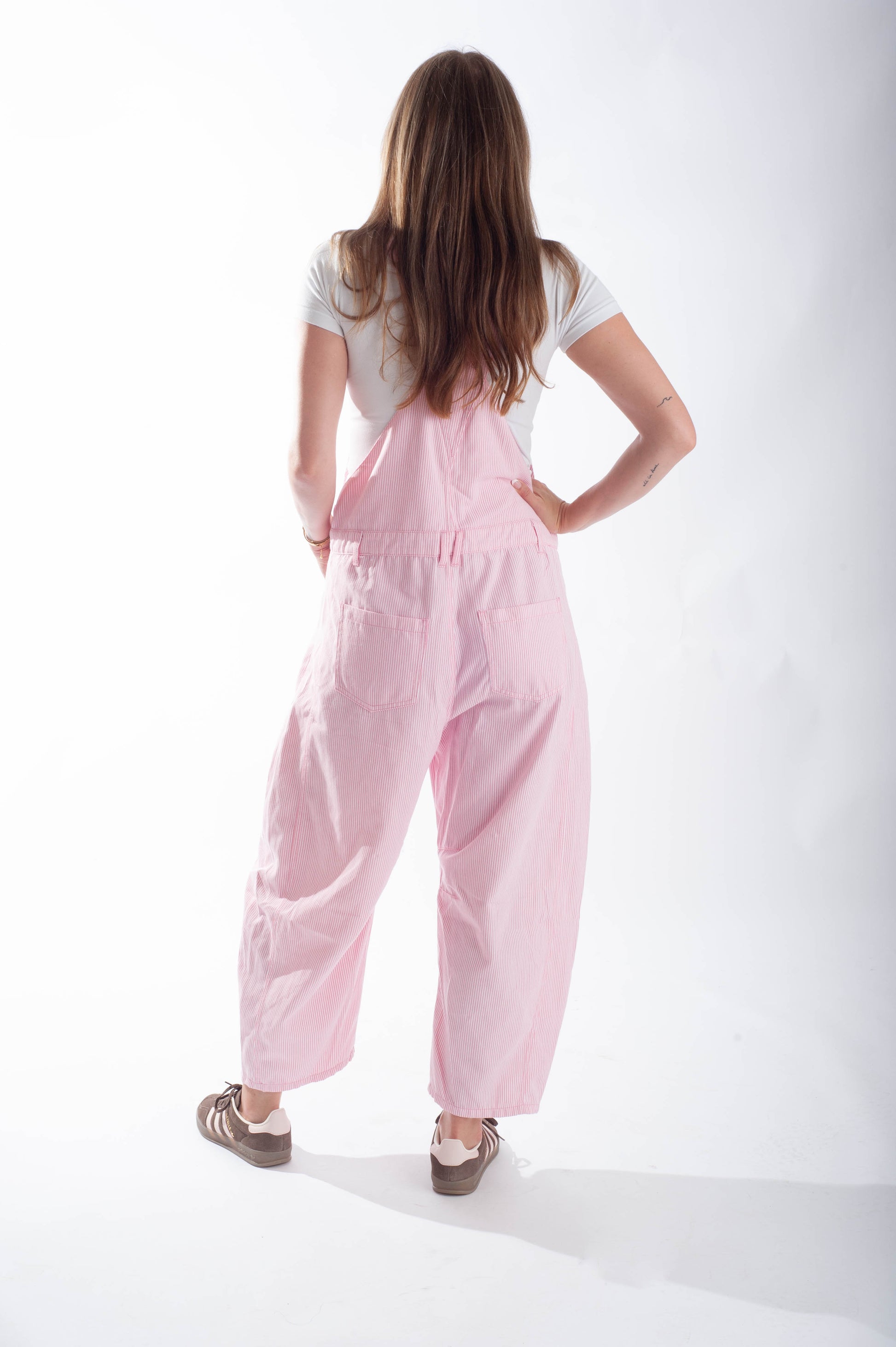 Person wearing a pink jumpsuit on a white background