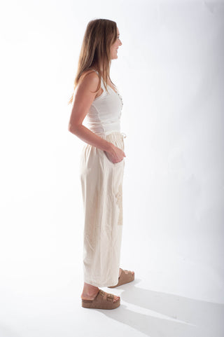 Woman wearing a white top and beige pants on a white background