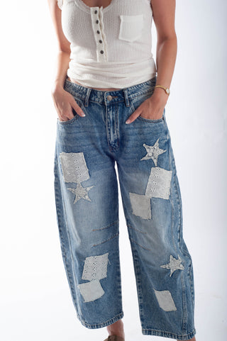 Blue jeans with star and square patches worn by a person on a white background
