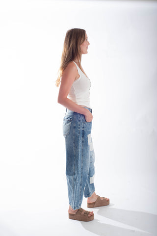 Woman wearing a white top and blue jeans standing against a white background