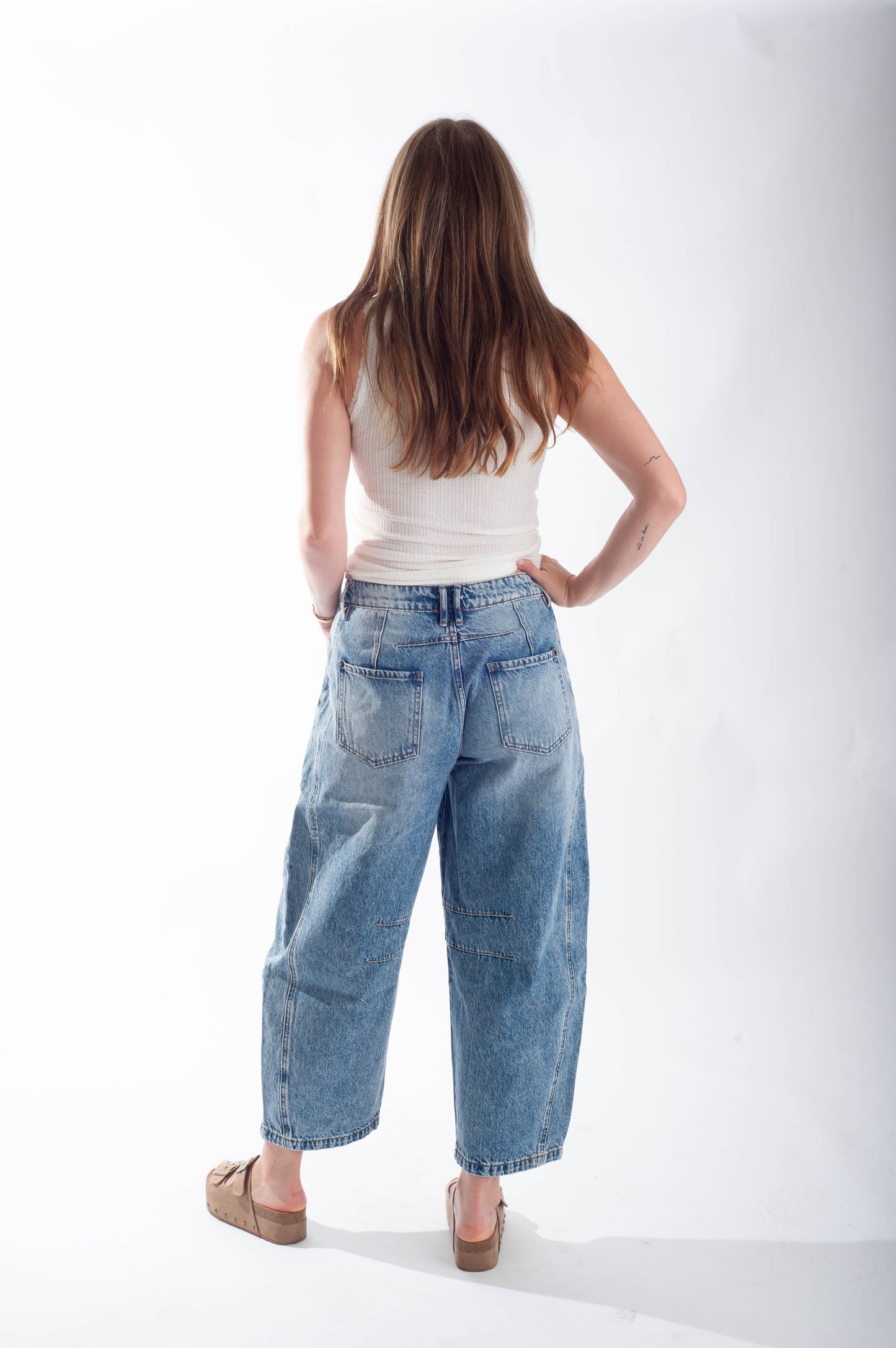 Woman wearing blue jeans and a white top on a white background