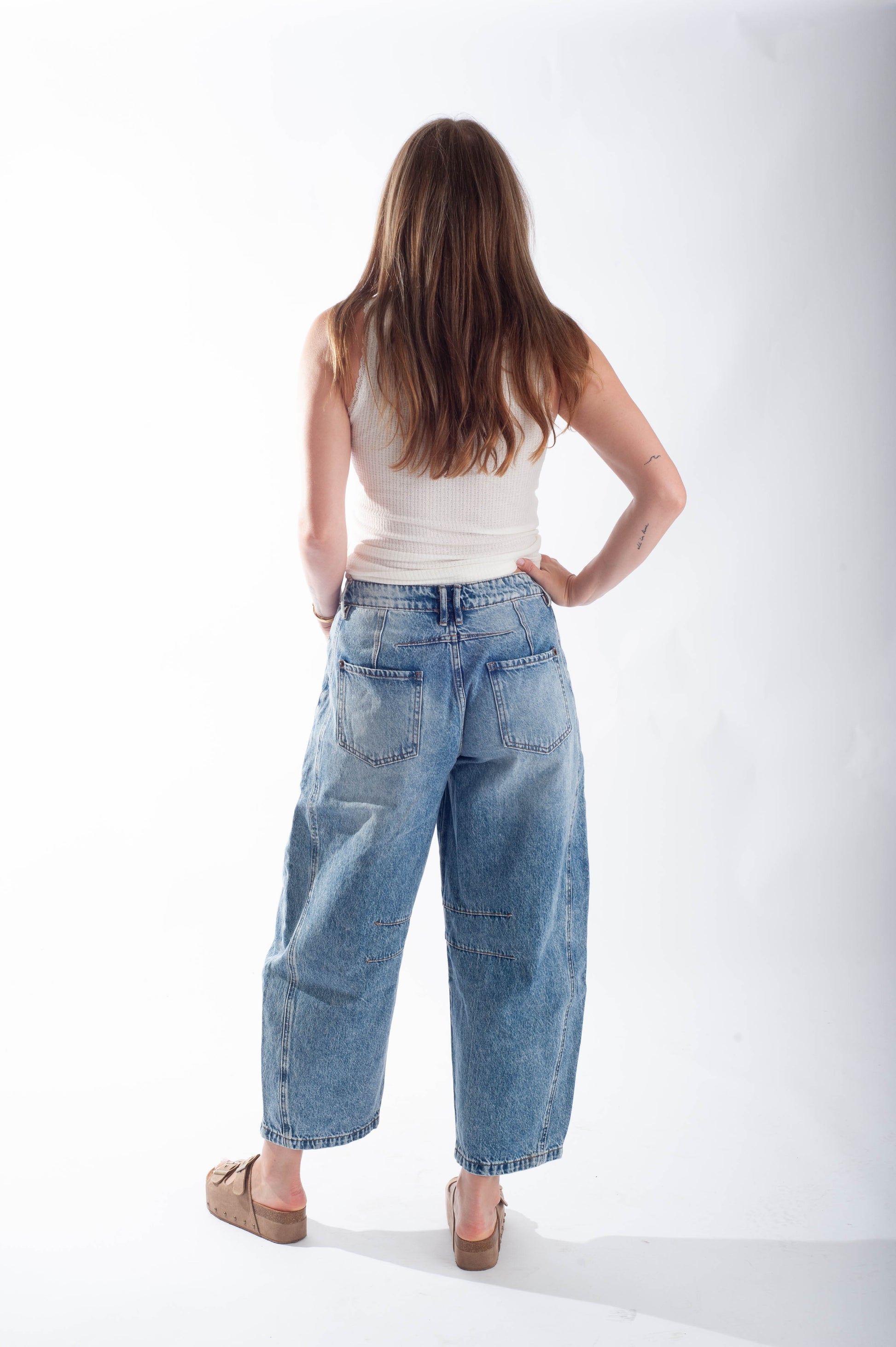 Woman wearing blue jeans and a white top on a white background