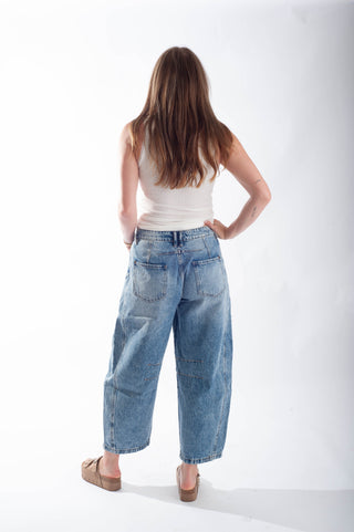 Woman wearing blue jeans and a white top on a white background