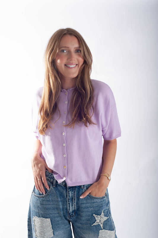 Woman wearing a light purple shirt and blue jeans with star designs on a white background