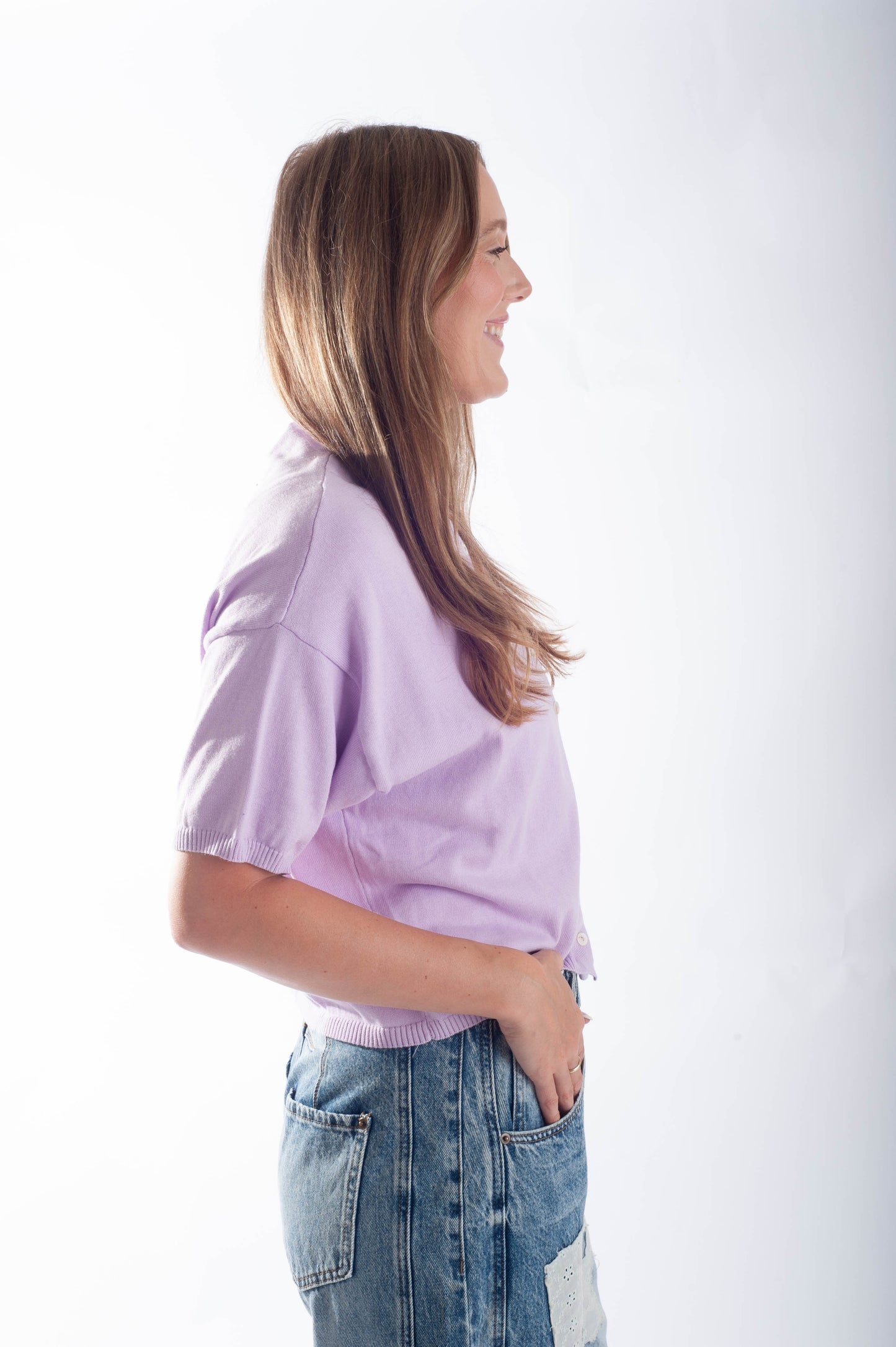 Woman wearing a light purple shirt and blue jeans on a white background
