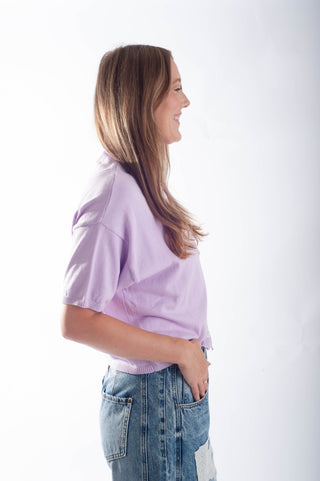Woman wearing a light purple shirt and blue jeans on a white background