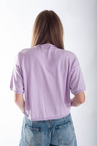 Person wearing a light purple sweater and blue jeans against a white background