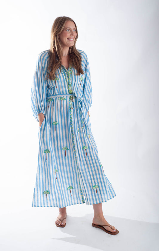 Woman wearing a blue and white striped dress with floral patterns on a white background