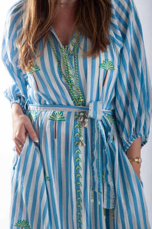 Woman wearing a blue and white striped dress with green patterns against a white background
