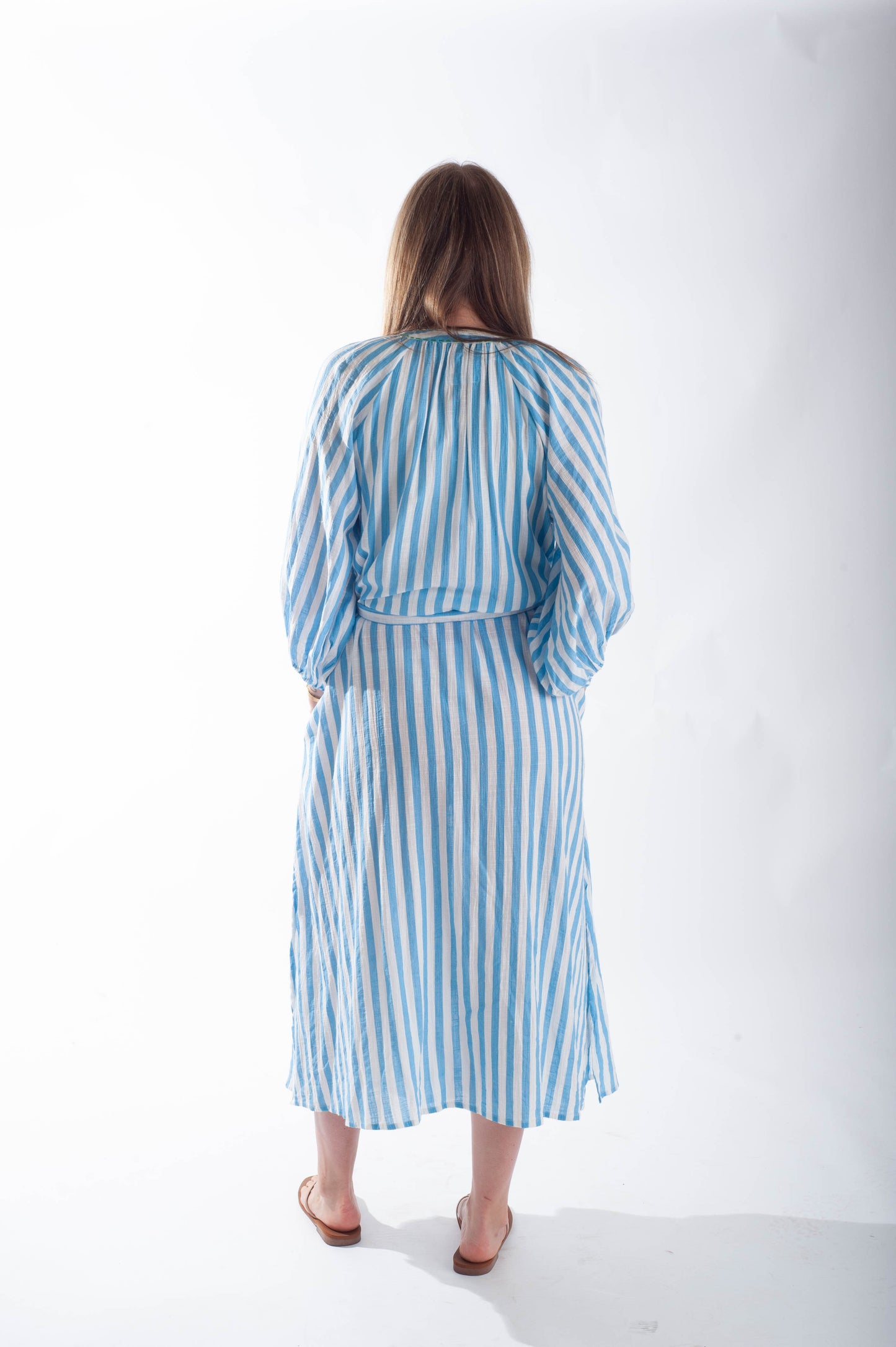 Woman wearing a blue and white striped dress on a white background