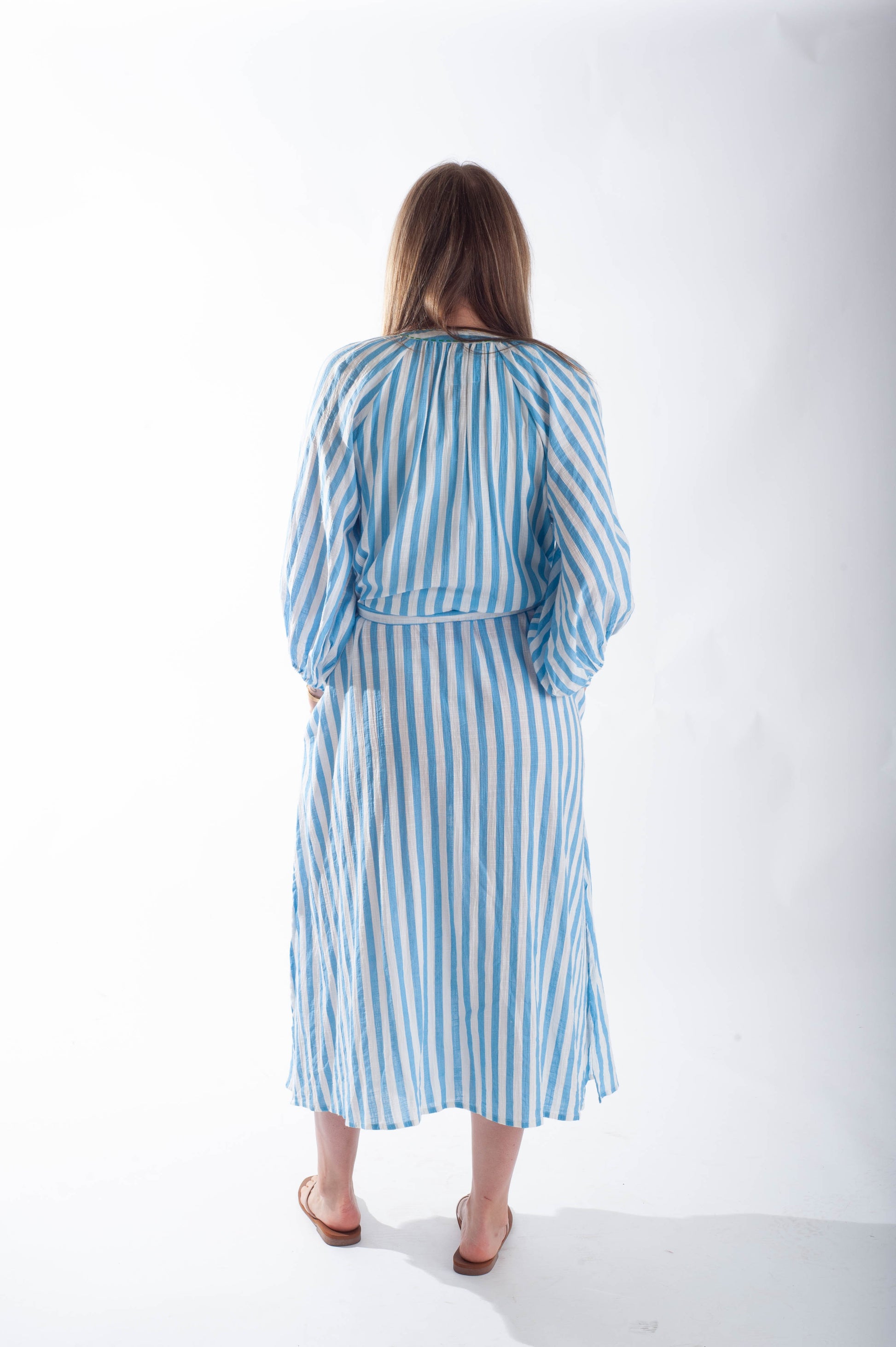 Woman wearing a blue and white striped dress on a white background