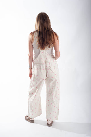 Woman wearing a white sleeveless top and wide-leg pants with a subtle pattern on a white background