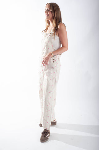 Woman wearing a white floral jumpsuit on a white background