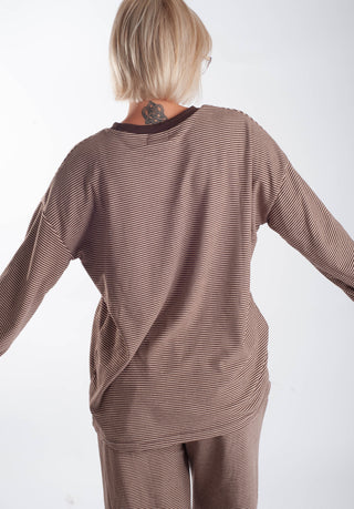 A person shown from the back wearing a brown and beige horizontally striped long-sleeve top and matching pants against a plain white background.