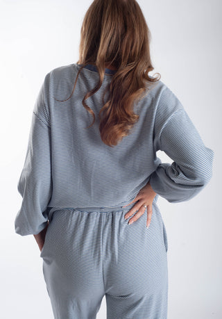 A woman shown from the back wearing a matching gray and white striped lounge set, featuring a long-sleeve top and pants, against a plain white background.