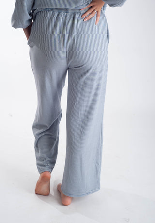 A person wearing light blue and white striped lounge pants, shown from the back against a plain white studio background.
