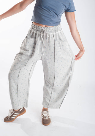 Women wearing grey floral barrel pants against a white background.