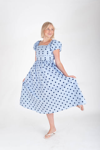 Woman wearing a blue polka dot dress on a white background