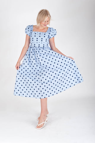 Woman wearing a blue polka dot dress on a white background