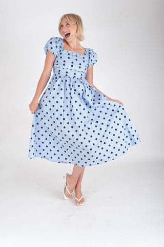 Woman wearing a blue polka dot dress on a white background