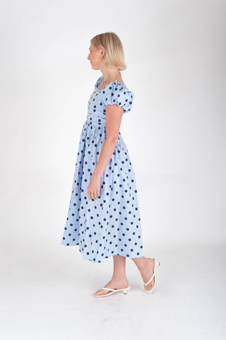 Woman wearing a blue polka dot dress on a white background