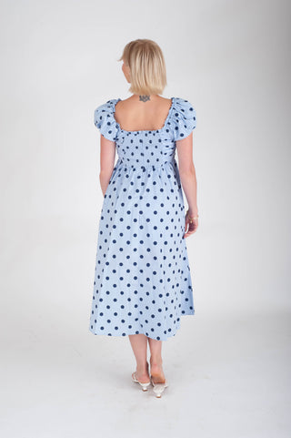 Woman wearing a blue polka dot dress on a white background