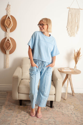 Woman in a light blue outfit standing in a room with decor elements.