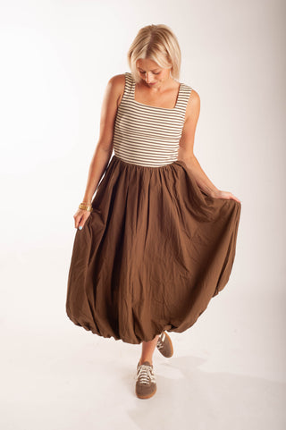 Women wearing a striped midi dress against a neutral background.