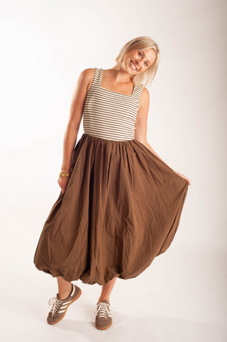Women wearing a striped midi dress against a neutral background.