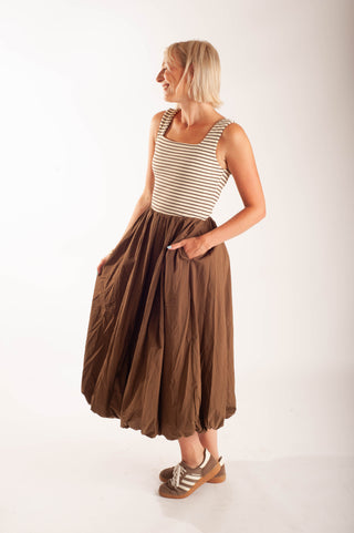 Women wearing a striped midi dress against a neutral background.