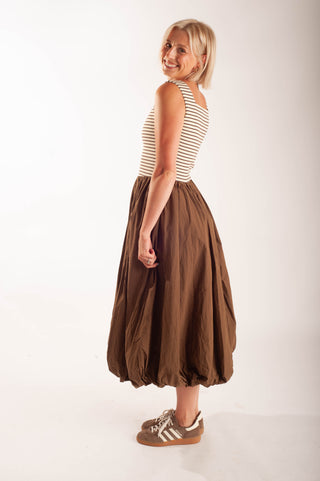 Women wearing a striped midi dress against a neutral background.