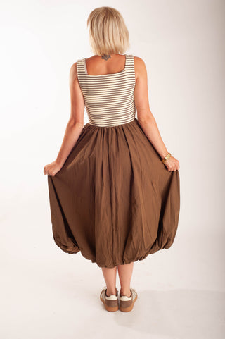 Women wearing a striped midi dress against a neutral background.