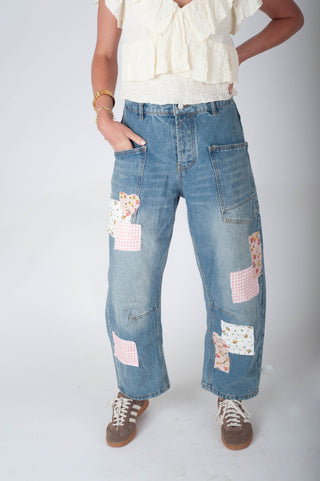 Person wearing blue jeans with floral patches on a white background