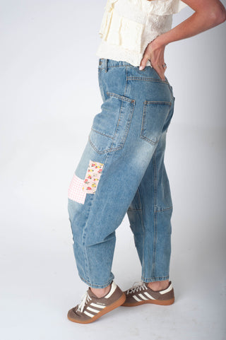 Person wearing blue patchwork jeans on a white background
