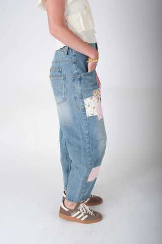 Person wearing patchwork jeans on a plain background