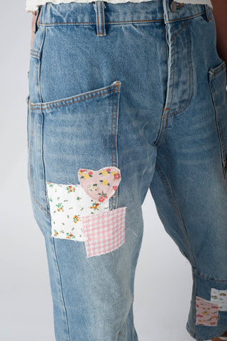 Blue jeans with floral and checkered patchwork on a white background