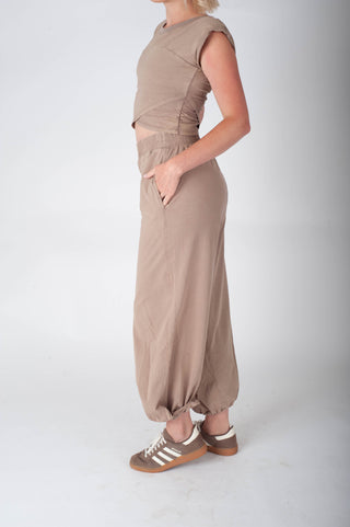 Person wearing a beige outfit with wide-leg pants on a white background