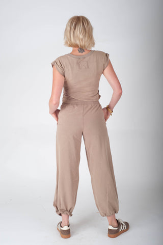 Woman wearing a beige jumpsuit on a white background