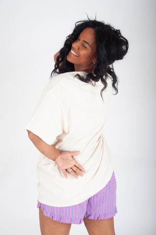 Woman wearing a white top and purple striped shorts on a white background