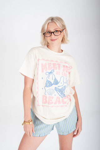 Woman wearing a graphic t-shirt with a bikini design and 'Meet Me at the Beach' text on a white background.