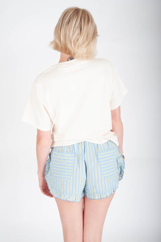 Person wearing a white t-shirt and light blue striped shorts on a plain background