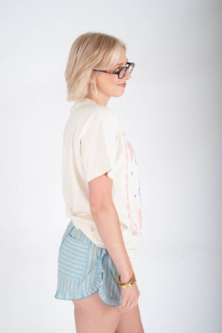 Woman wearing a white blouse and striped shorts on a plain background